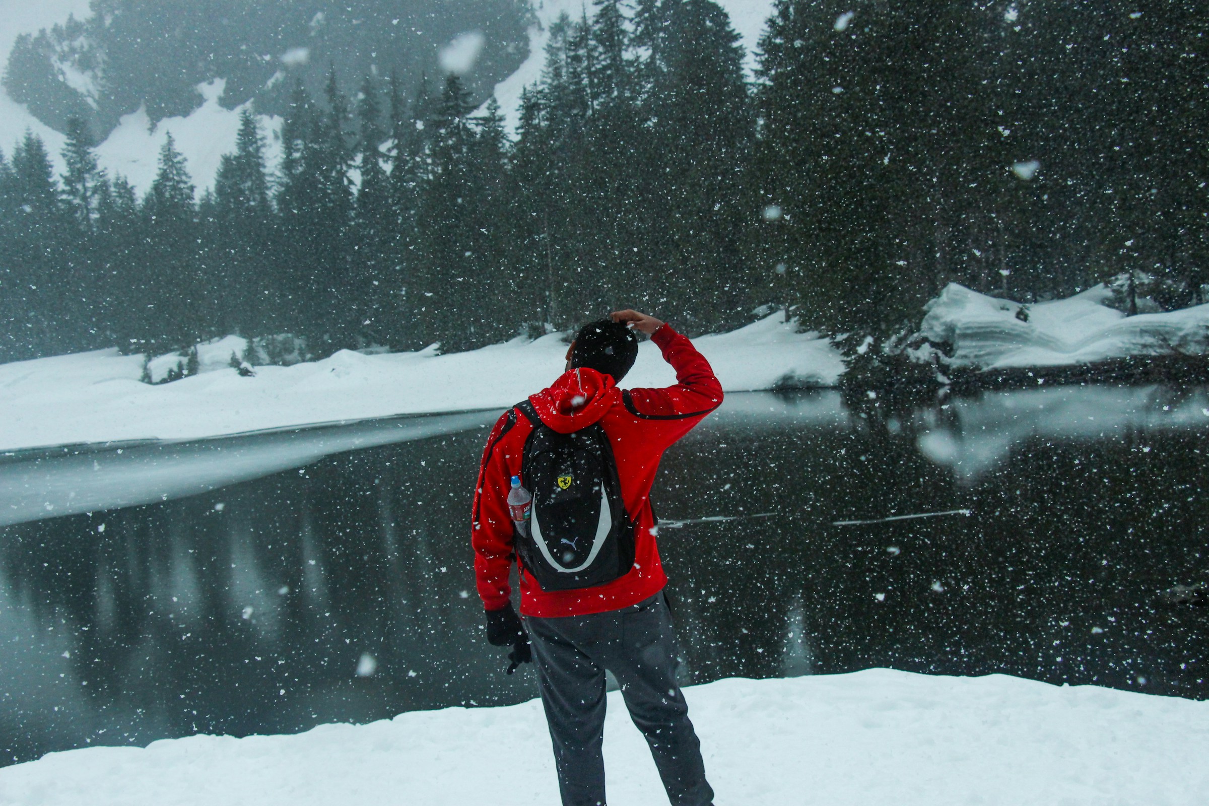 Wanderer mit roter Jacke in schneebedeckter Winterlandschaft